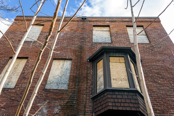 An old red-brick house with boarded windows is ready for demolition or renovation in spring.