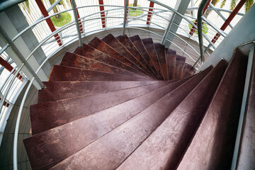 Top view of a spiral wooden staircase in a tower with windows. Old shabby brown circular stairs...