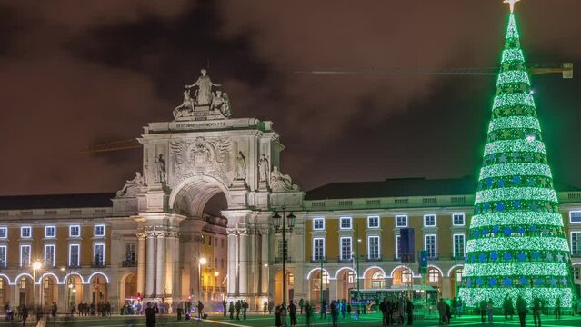 Commerce square illuminated and decorated at Christmas time in Lisbon night timelapse hyperlapse. Commercio square with christmas tree and people tourists crowd around, city of europe