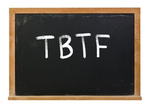 Too Big to Fail written in white chalk on a black chalkboard isolated on white