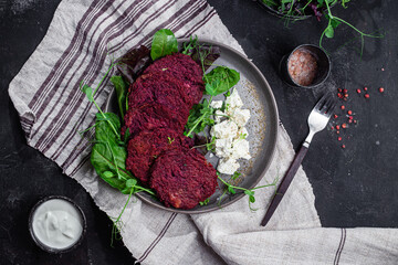Beetroot pancakes with feta and herbs on a dark plate