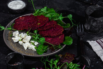 Beetroot pancakes with feta and herbs on a dark plate