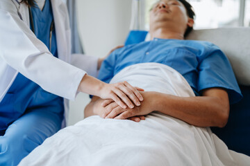 Obraz premium Female doctor holding male patient hand on the bed with receiving saline solution in hospital .