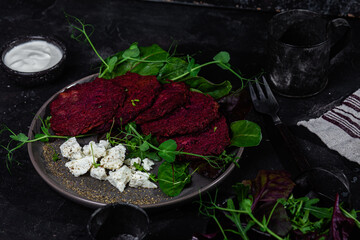 Beetroot pancakes with feta and herbs on a dark plate