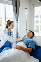 Obraz premium Doctor in white suit take notes while discussing and Asian elderly, man patient who lying on bed with receiving saline solution in hospital or clinic..