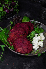 Beetroot pancakes with feta and herbs on a dark plate