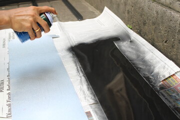 Obraz premium A worker painting metal sheet in black with spray paint or aerosol paint