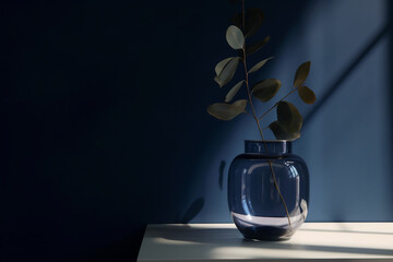 Contemporary design with a glass vase and dried eucalyptus leaves on a dark blue wall