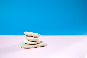 white stones as a podium for beauty products on soft pink table against turquoise background