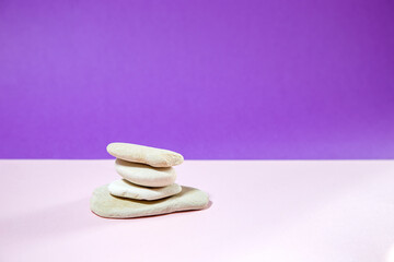 white stones as a podium for beauty products on soft pink table against purple background
