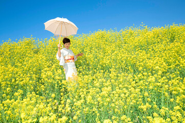 Fototapeta premium Japanese woman in a beautiful yellow flowers field