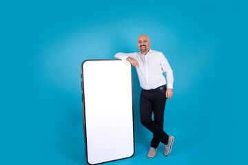 Big cell phone mock up, cheerful middle aged man leaning big cell phone mock up. Empty white screen smartphone for product placement. Application, web site advertising concept idea, copy space.