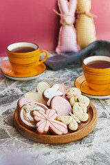 Fototapeta na wymiar Aesthetics Easter glazed cookies, cups of tea on the decorated table. Holiday tea time