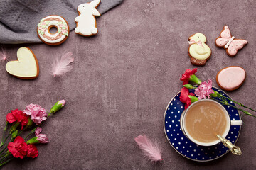 Easter aesthetic coffee time. Glazed cookies, coffee cup, feathers, aster flowers flat. lay. Spring stylish background with copy space