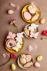 Decorated aesthetic Easter cookies, pink flowers with feathers and eggs. Spring pastel background