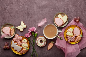 Spring aesthetic Easter background complete coffee cup, decorated glazed cookies, feathers and aster flowers flat lay with copy space. Spring background