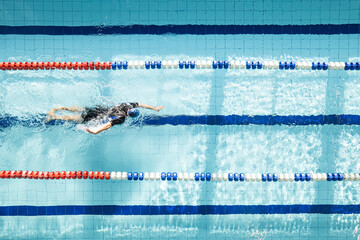 Top view shot of young man swimming laps in a swimming pool. Male swimmer swimming the front crawl...