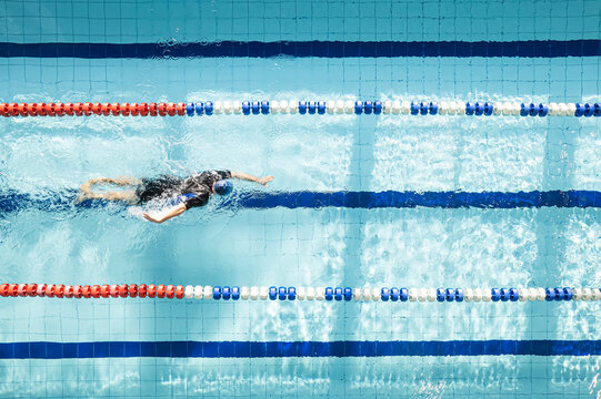 Top view shot of young man swimming laps in a swimming pool. Male swimmer swimming the front crawl in a pool. Swimming pool for sports swimming.