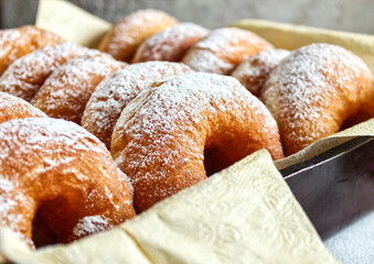 Doughnuts with powdered sugar on a tray, selective focus.  Delicious homemade donuts, close-up. A traditional Hanukkah treat. The concept of celebrating Hanukkah. A place to copy.