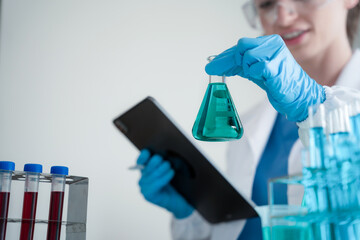 Chemist scientist holding test tube and tablet conducting experiment in laboratory with equipment, science concept.