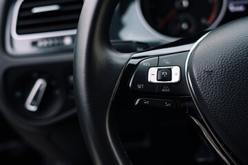 Modern car interior, control details, aluminum, leather steering wheel.