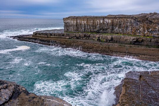 White waves on a blue Irish rocky cliff in a blue sky dasy