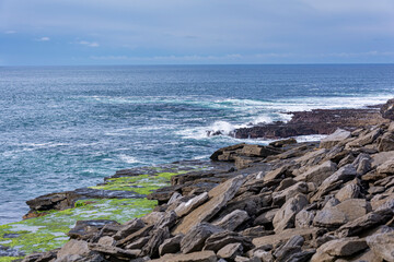 White waves on a blue Irish rocky cliff in a blue sky dasy