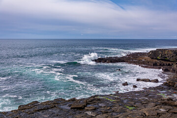White waves on a blue Irish rocky cliff in a blue sky dasy