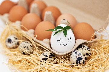 Easter holiday. Eggs in an eco box, one egg with a smile, quail eggs on straw.