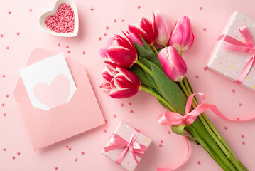Mother's Day concept. Top view photo of bouquet of tulips present boxes with bows envelope postal with heart and saucer with sprinkles on isolated pastel pink background