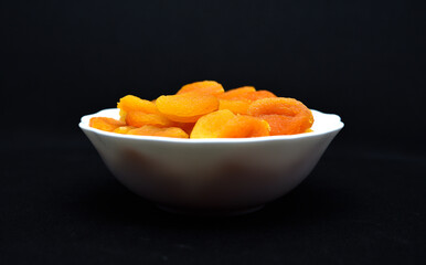 Juicy dried apricots in a white ceramic bowl. Dried apricot fruit halves without a stone.