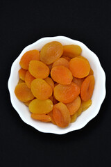 Juicy dried apricots in a white ceramic bowl. Dried apricot fruit halves without a stone.