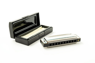 Harmonica, also French harp, blues harp, isolated on white background with its case. Free reed wind instrument used worldwide in blues, folk, jazz, rock and roll.