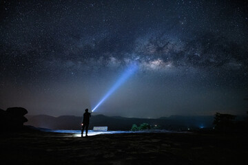 Traveler hiker who sitting top of mountain with lighting beautiful night starry sky milky way is...