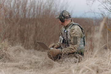 military man stands in camouflage and works with a laptop. military intelligence