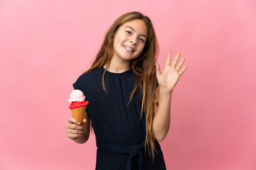Child with a cornet ice cream over isolated pink background saluting with hand with happy expression