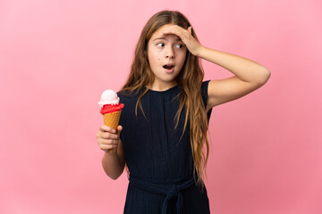 Child with a cornet ice cream over isolated pink background doing surprise gesture while looking to...