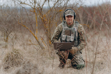 military man stands in camouflage and works with a laptop. military intelligence