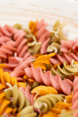 Rice vegetable pasta in the form of spirals in a bowl. Healthy rice pasta with tomatoes, selenera, carrots and beets