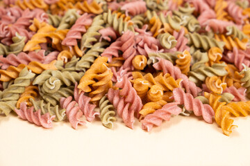 Rice vegetable pasta in the form of spirals on a white background. Healthy rice pasta with tomatoes, selenera, carrots and beets