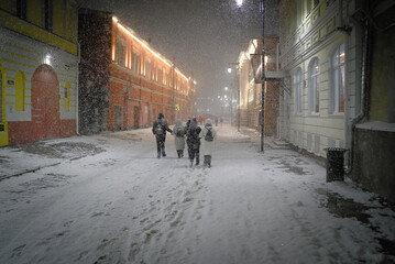 A snowstorm while walking along the ancient city streets. A group of people walking at night...