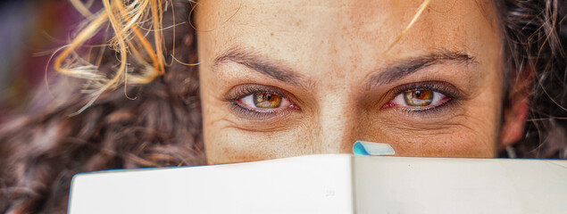 Close-up of the eyes of a woman covered with a book. World day of the book. sant jordi day