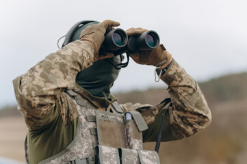 Fototapeta premium war, army, hunting. young soldier, ranger or hunter with binoculars watching the forest