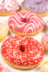 Donuts with red and pink glaze, top view. Lots of donuts, sweet and delicious food