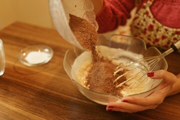 Close-up view of adding cocoa powder to the pastry dough. The moment of spilling the cocoa powder while making the cookie dough.