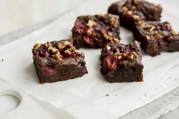 Chocolate brownie with cherries and berries nuts on top on white background close up selective focus