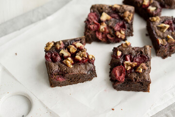 Chocolate brownie with cherries and berries nuts on top on white background close up selective focus