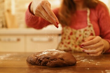 Image of hand sprinkling flour on dough. Close-up of woman sprinkling flour on the dough she kneaded in the kitchen.