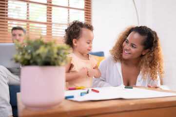 A little child's imagination is represented through colored pencil drawings, with the parents attentively supervising in the living room of the house.