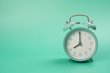 Retro alarm clock on green table background, vintage style, flat lay